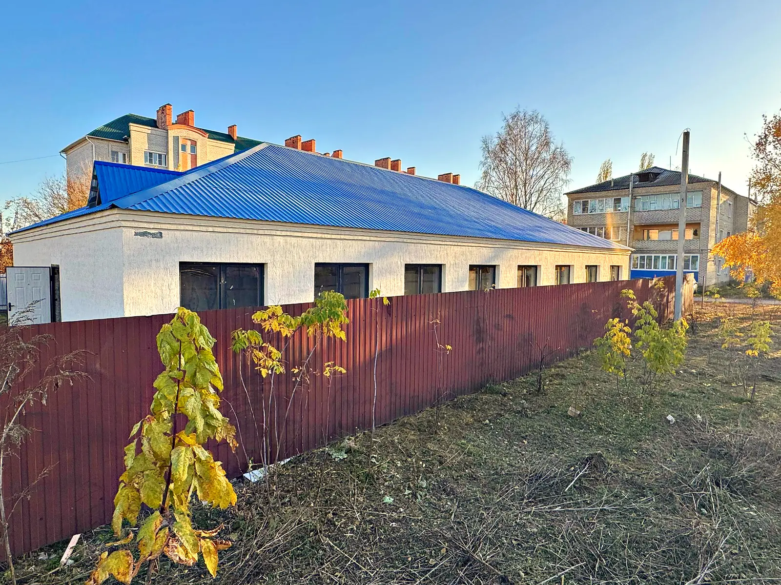 Здание с дороги: белые стены, синяя кровля